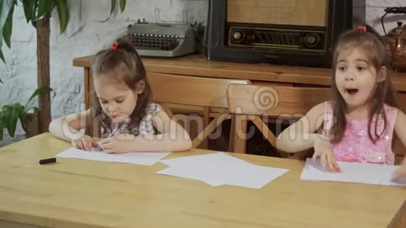 两个小女孩笑着在木桌旁画画视频的预览图
