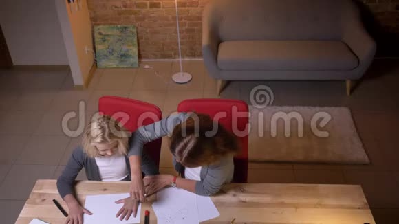 一位年轻的白种人母亲在她漂亮的小女儿身边画着一幅画手拿着它对着一个视频的预览图