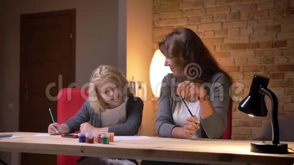 年轻的白种人母亲和她美丽的小女孩的特写镜头在室内欢笑和消磨时光视频的预览图