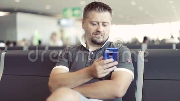 一个留着胡子的人坐在机场用手机视频的预览图