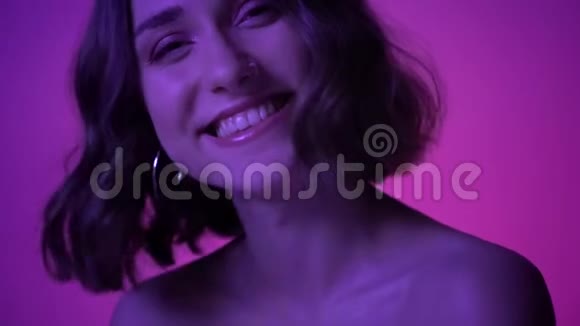 拍摄的年轻漂亮女性在镜头前欢快地笑着镜头背景为霓虹灯紫色视频的预览图