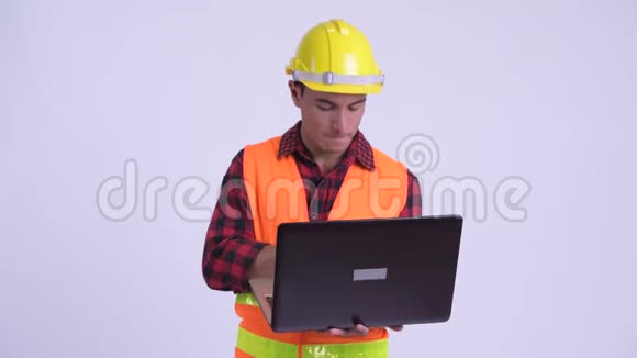 年轻快乐的西班牙裔建筑工人在使用笔记本电脑时思考视频的预览图
