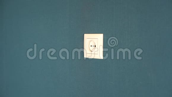 一个男人把电话充电器插入墙上的插座墙上贴着深蓝色壁纸的罗塞特视频的预览图
