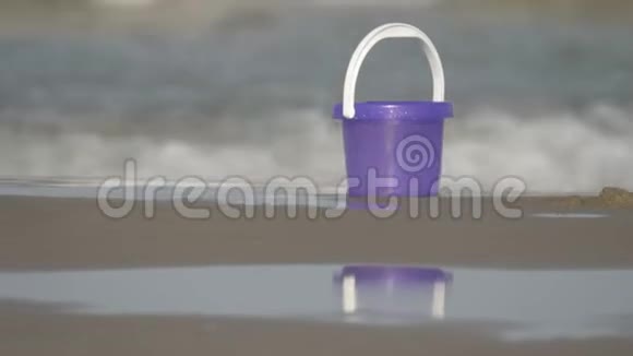沙滩上的一个紫色玩具桶背景上波光粼粼视频的预览图