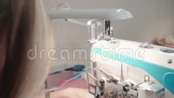 女裁缝在工厂的电动机器上缝制粉红色的衣服视频的预览图