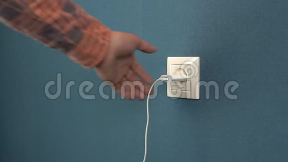 一个男人从墙上的插座里掏出一个电话充电器墙上贴着深蓝色壁纸的罗塞特视频的预览图