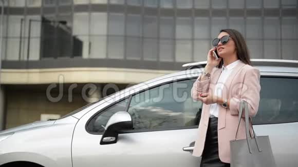 一位忙碌的商务女士站在她的车旁边用手机交谈然后她看着她的腕表视频的预览图