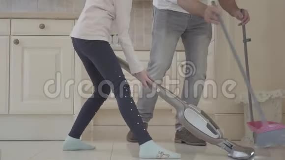 爸爸和女儿在干净的房子里玩得很开心一个拿着扫帚和簸箕的男人和一个拿着吸尘器的女孩消遣时间视频的预览图