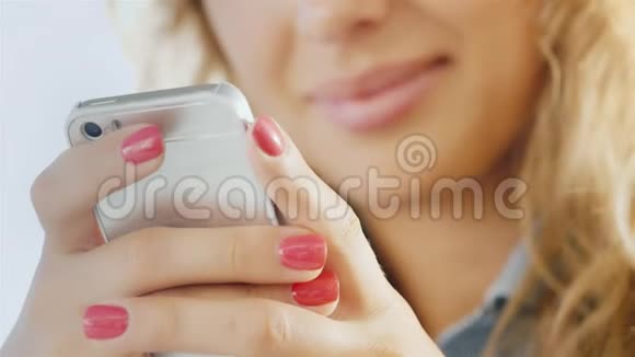 一个年轻女子手里拿着手机微笑的嘴唇微微模糊视频的预览图