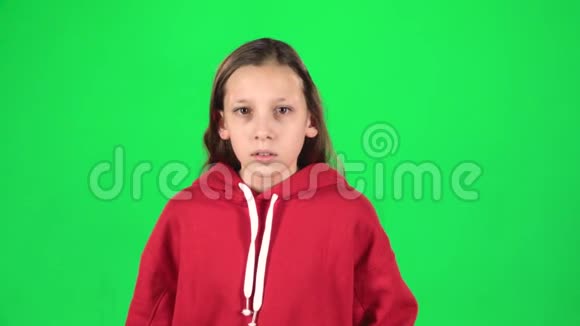 小女孩害怕把脸藏在绿色背景的工作室里慢动作视频的预览图