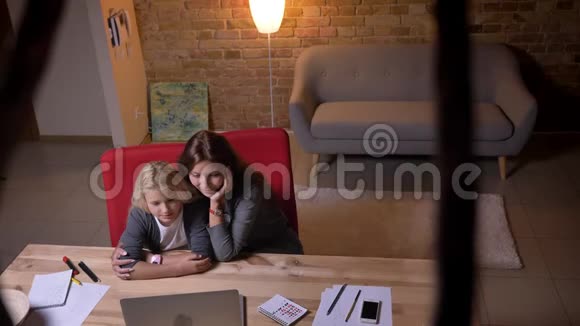 一位年轻的白种人女性和她的小女儿在笔记本电脑上看电影的特写镜头微笑着视频的预览图