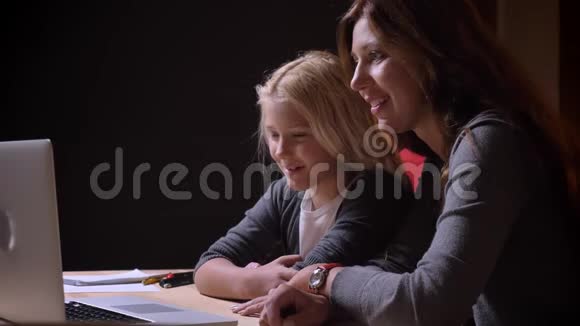 年轻的白种人母亲和她漂亮的小女孩在笔记本电脑上看电影笑了起来视频的预览图