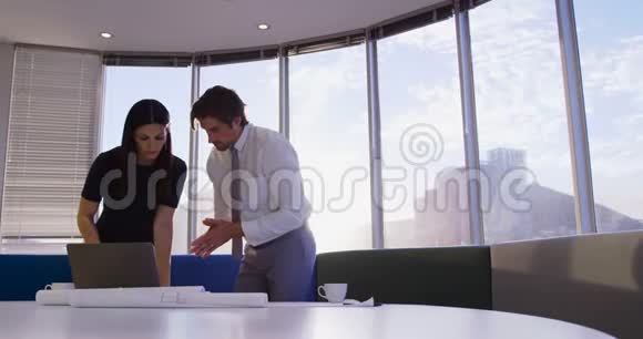 白种人年轻的办公室管理人员在办公室4k的桌子上使用笔记本电脑和蓝图视频的预览图