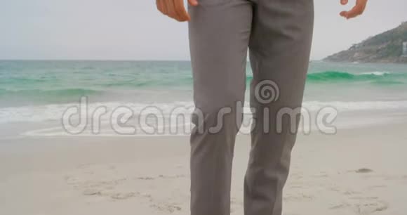 白人商人拿着他的公文包在海滩4k的低角度视野视频的预览图