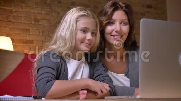 年轻母亲和女儿在笔记本电脑上看电影的特写镜头在家里笑嘻嘻视频的预览图