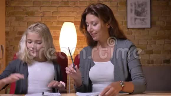 年轻的白种人母亲和她的女儿在一起帮助她做家庭作业的特写镜头妈妈和视频的预览图