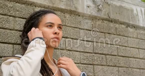 城市中戴耳机的年轻非洲裔美国妇女的正面景色视频的预览图
