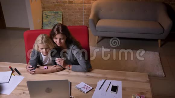特写镜头年轻的白种人母亲和她的女儿在笔记本电脑上看电影笑妈妈轻轻地视频的预览图