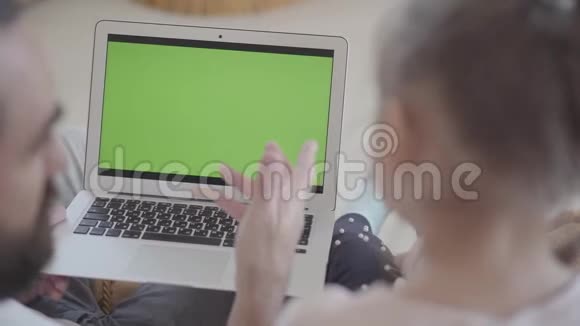 爸爸和可爱的小女儿在笔记本电脑上用空白的复印空间屏幕看和搜索东西视频的预览图