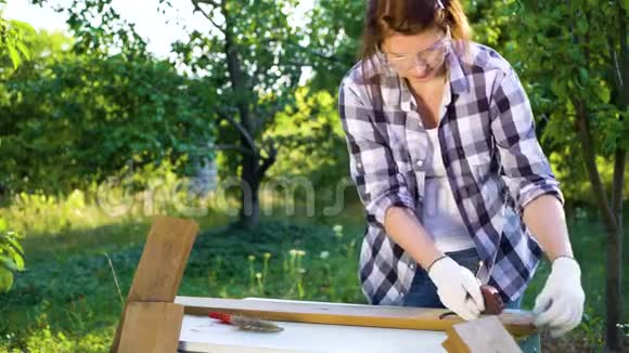 女木匠在阳光明媚的花园里用卷尺测量木板视频的预览图