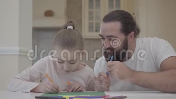 一个留着胡子的男人坐在家里的桌子旁看着他用记号笔画的小女孩父亲建议视频的预览图
