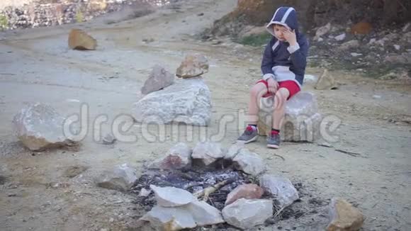 孤独的孩子坐在山火旁视频的预览图