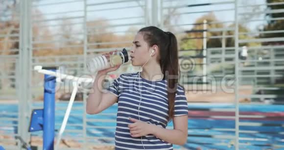 女孩在训练一瓶饮料后很累漂亮的女人正在喝一杯摇床上的饮料视频的预览图