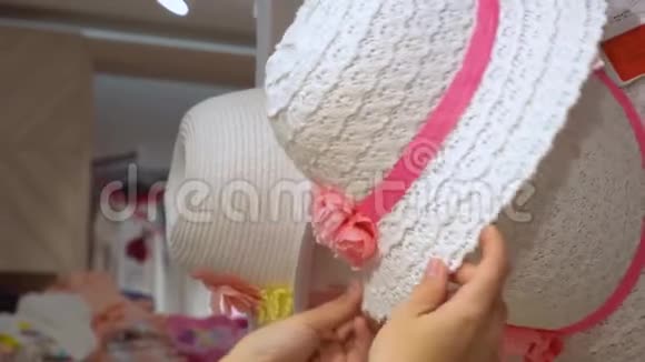 女人在商店里挑选帽子手的近景视频的预览图