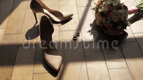地板上有一束鲜花金制的结婚戒指阳光透过窗户洒下来女人鞋子婚礼安排视频的预览图