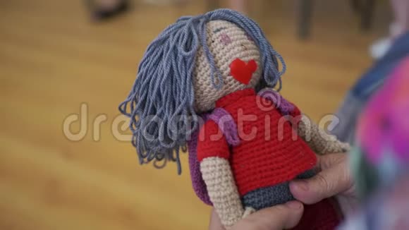 双手握着针织娃娃合上老奶奶手中的手工娃娃视频的预览图