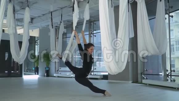 美丽的微笑女人有着迷人的身体在健身吊床上做反重力空中瑜伽视频的预览图