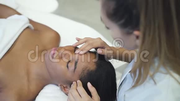 女性美容医生在水疗沙龙按摩非洲妇女的脸视频的预览图