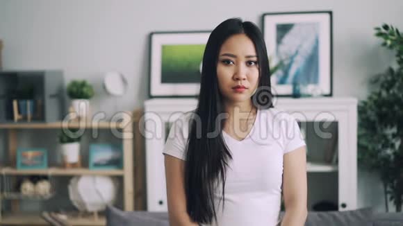 一幅美丽的亚洲女人的慢镜头肖像长发站在现代公寓里微笑着看着镜头视频的预览图