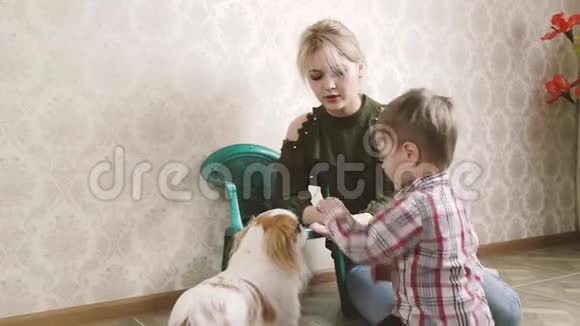有趣的宝宝和妈妈用手在舒适的家庭房间里喂狗饼干视频的预览图