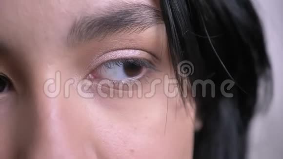 一张年轻迷人的白种人黑黑头发的女性脸的特写半脸肖像美丽的眼睛直视视频的预览图