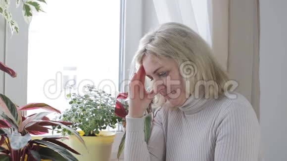 坐在窗边担心的女人揉了揉她的额头很紧张视频的预览图