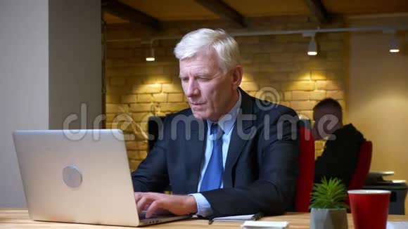 老白种人忙碌的商人在工作场所的办公室里使用笔记本电脑的特写镜头视频的预览图