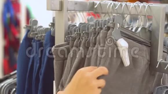 女人为商店里的男孩选择裤子手的近景视频的预览图
