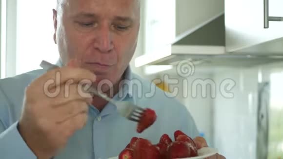 厨房里的男人微笑快乐吃美味可口的草莓水果视频的预览图