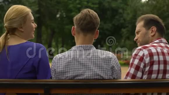 十几岁的儿子和父母坐在长凳上谈论假期信任视频的预览图