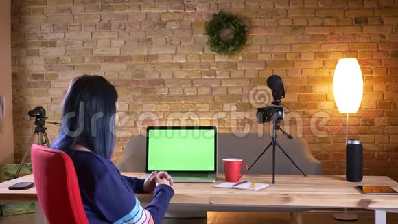 年轻有魅力的女性博客作者在笔记本电脑上现场直播室内有绿色屏幕视频的预览图