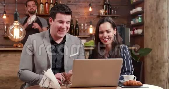 一个男人和一个年轻的女人在午休时看着笔记本电脑笑了视频的预览图