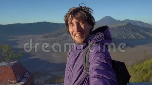一位年轻的博客写手在爪哇登格尔卡尔德拉的布罗莫火山上拍摄自拍视频视频的预览图