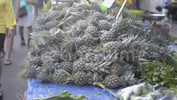 早市出售的一堆菠萝与在农贸市场行走的人们一起销售农产品视频的预览图