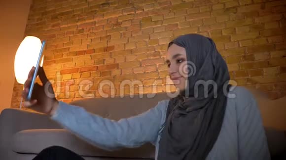 年轻迷人的穆斯林女性少女坐在电话里自拍的特写自下而上拍摄视频的预览图