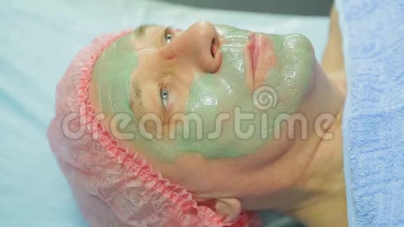 一位女性美容师用刷子把泥面具涂在男人的脸上侧视视频的预览图