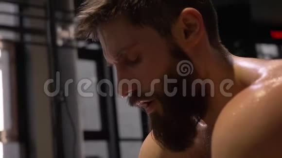 成人肌肉运动男子坐在健身房里流汗的特写镜头视频的预览图