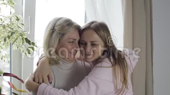 母女俩站在窗边笑着拥抱视频的预览图