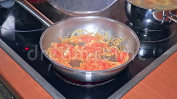 将番茄酱与切碎的番茄和洋葱一起放入锅中厨师用木铲将其固定视频的预览图