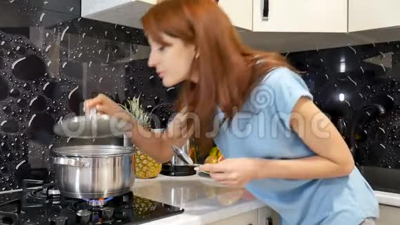 迷人的年轻妻子站在厨房的炉子旁做饭闻着她在锅里的饭菜的香味视频的预览图